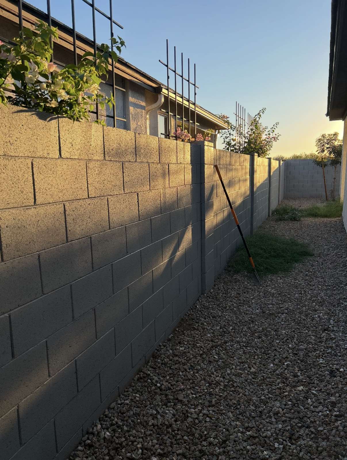 After: the same concrete block wall along the gravel side yard, fully painted gray